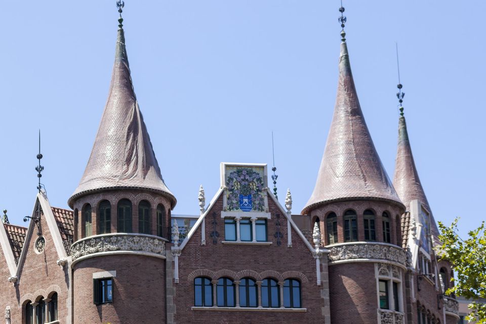 Brick building with conical slate towers and a coat of arms