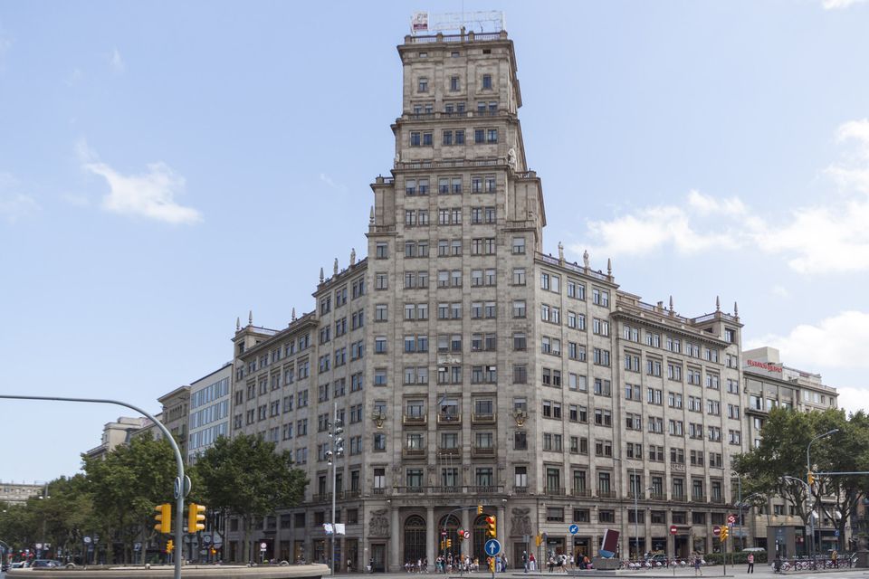 Tall stone office building on a street corner in sunshine