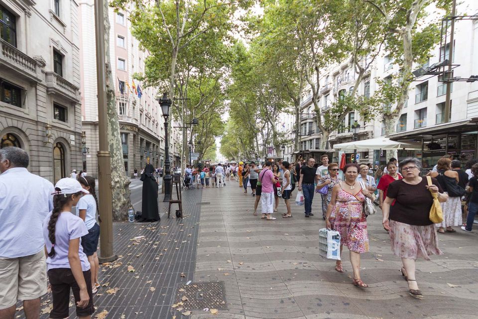Crowded tree-lined pedestrian boulevard with a long paved walkway