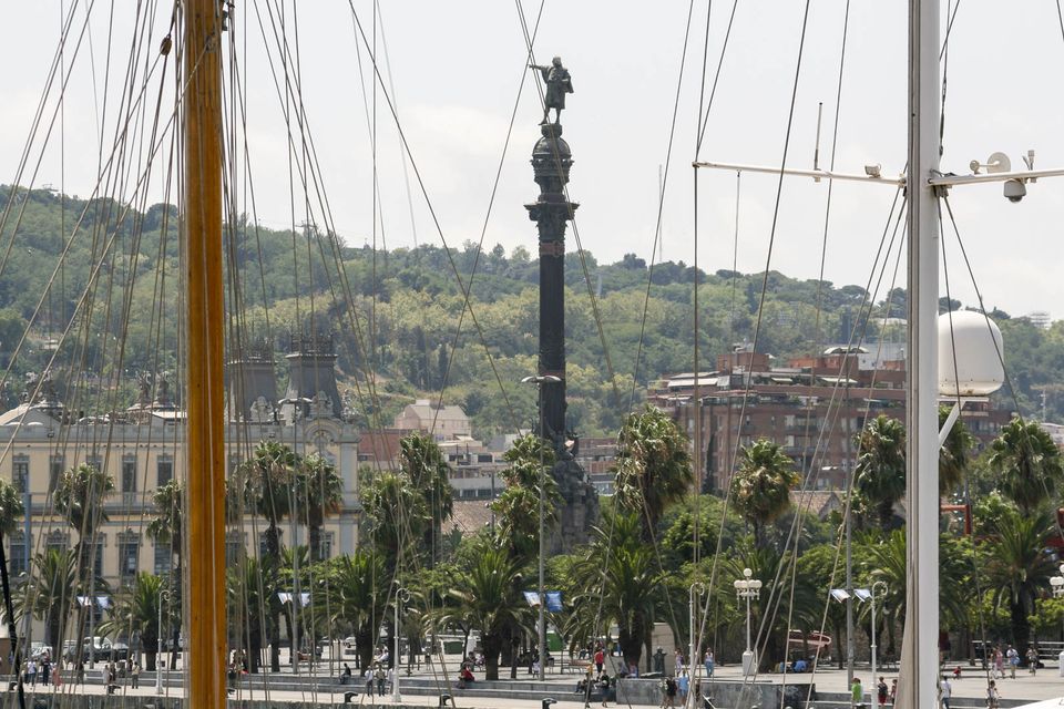 Columbus column behind palm trees and ship masts