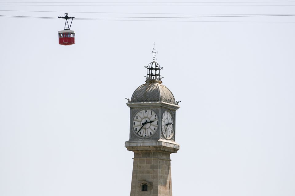 Stone clock tower with a red cable car above
