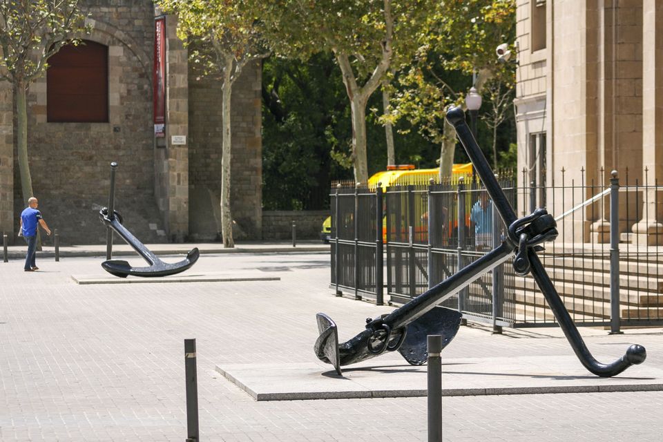 Two large black anchors on a paved square