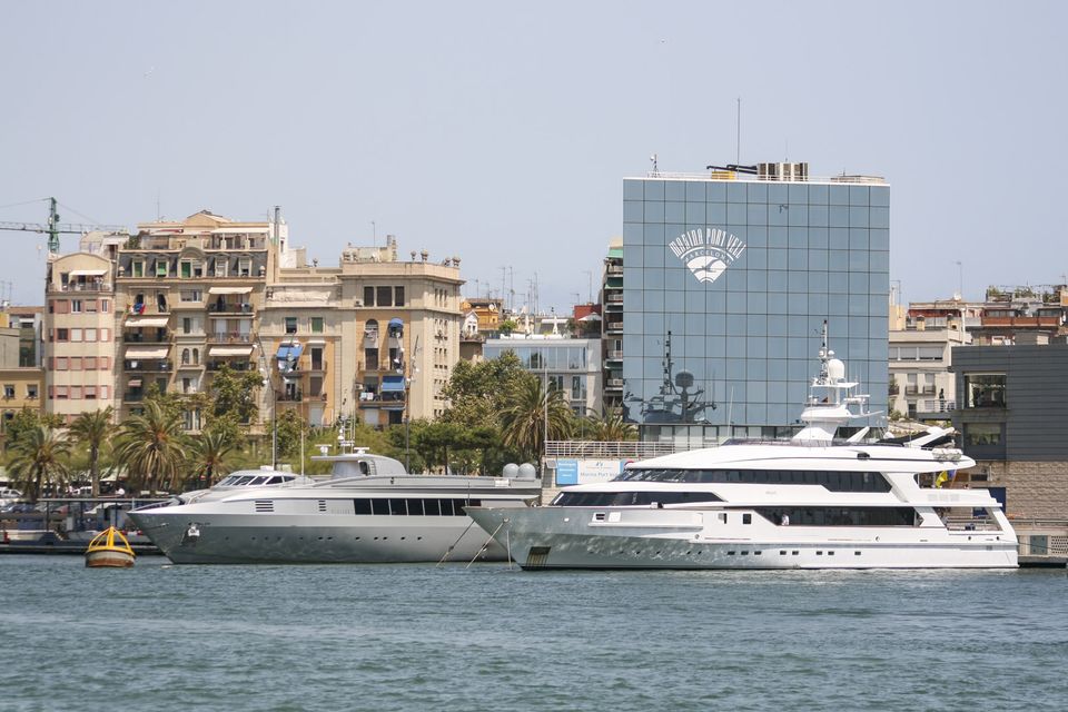 Luxury yachts moored before a glass office building and apartments