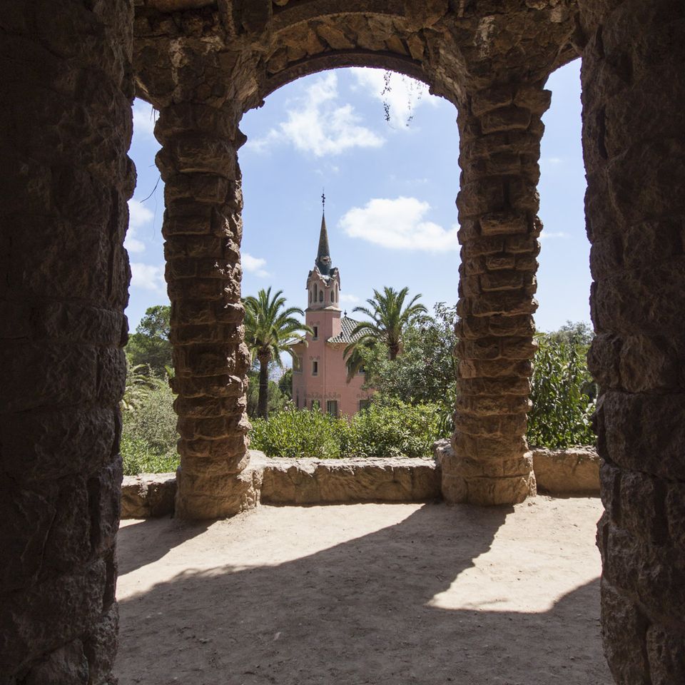 Pink tower framed by rough stone arches and palms