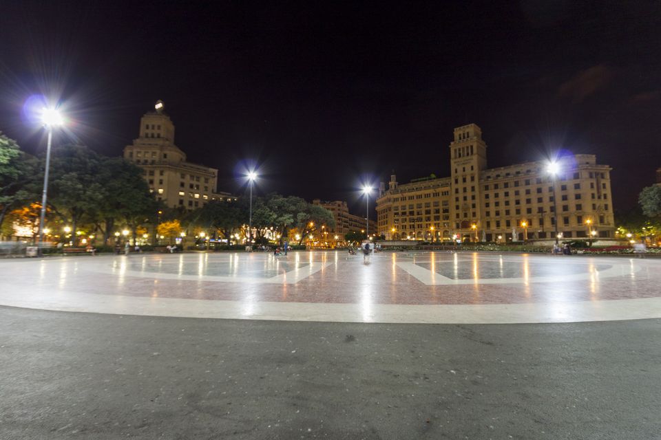 Empty plaza at night with lit buildings and street lamps