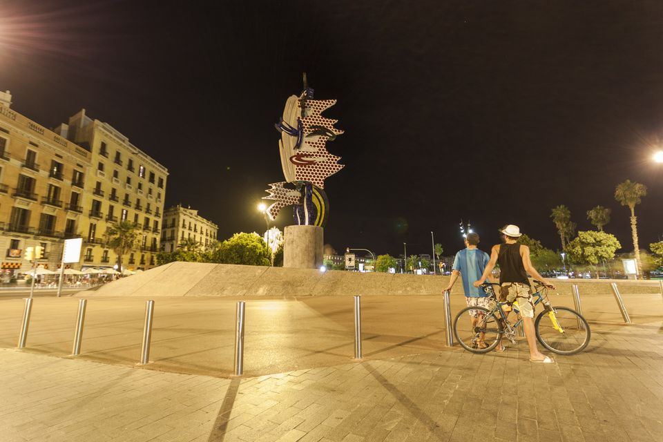 Mosaic head sculpture at night with two cyclists