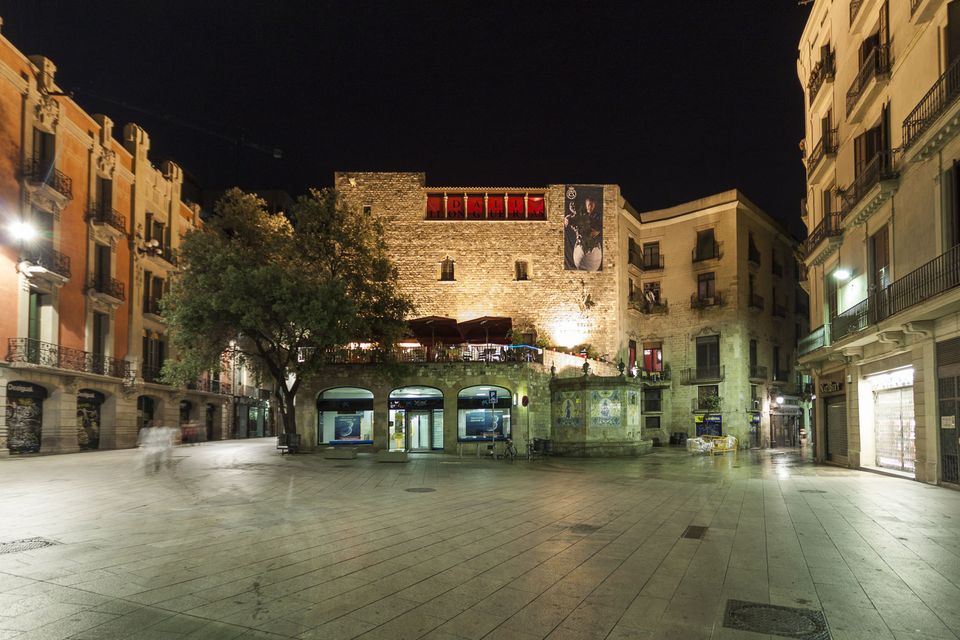 Stone-walled square at night with warm lit buildings