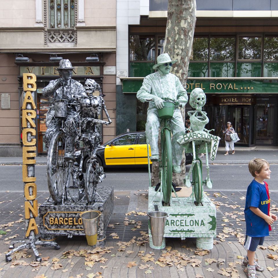 Living statues painted silver and green on bicycles