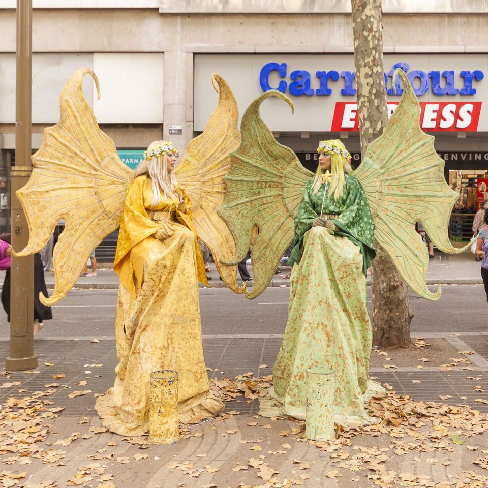 Two living statues in gold and green with large wings
