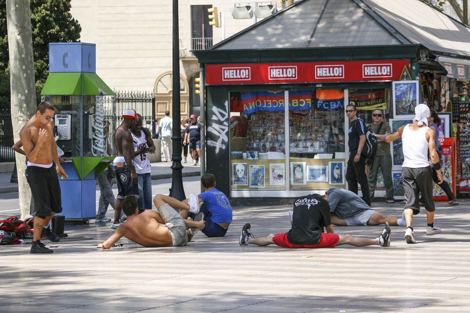 Break dancers stretching on the pavement outside a kiosk