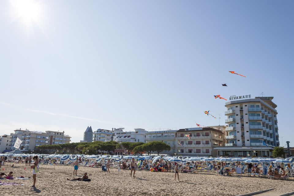 Kites flying above rows of umbrellas and beachfront hotels