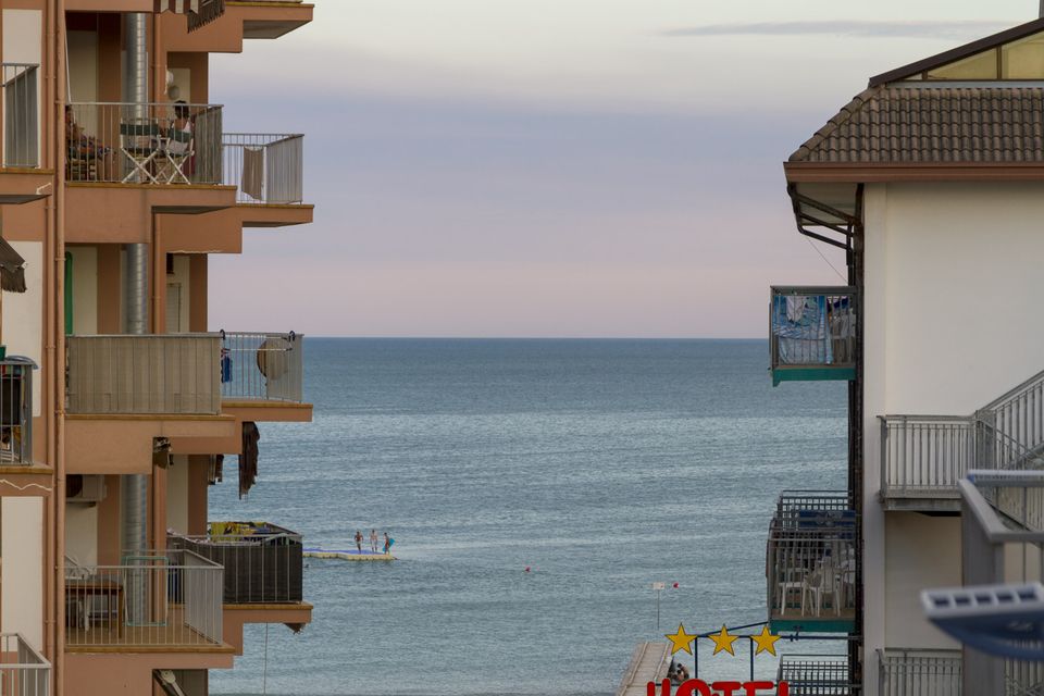 Strip of sea between hotel balconies, with a hotel sign below