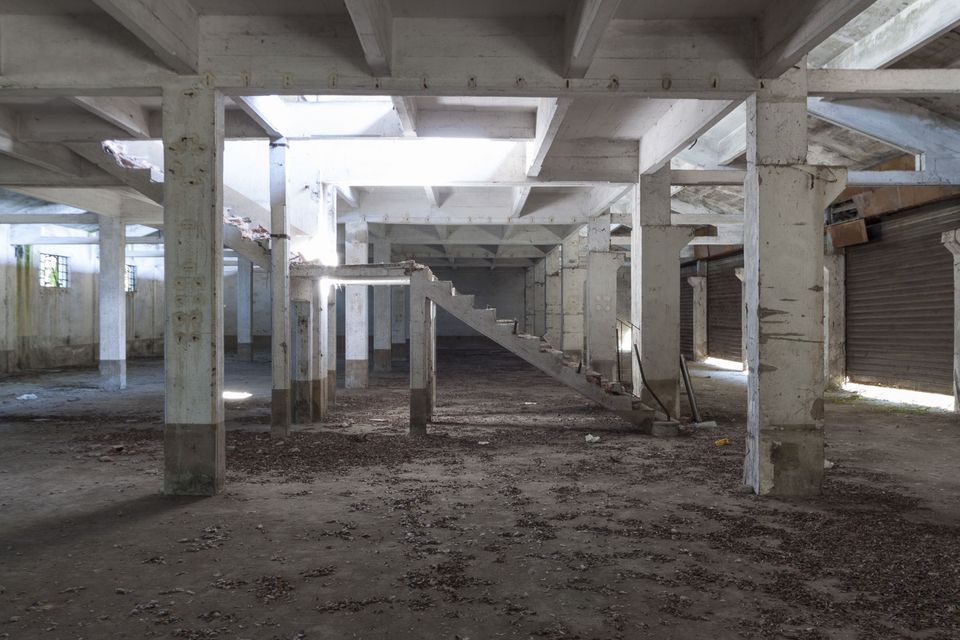 Concrete pillared hall with a staircase and shuttered openings