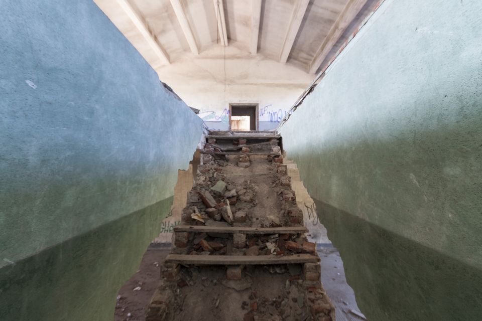 Broken staircase of rubble between green-painted walls