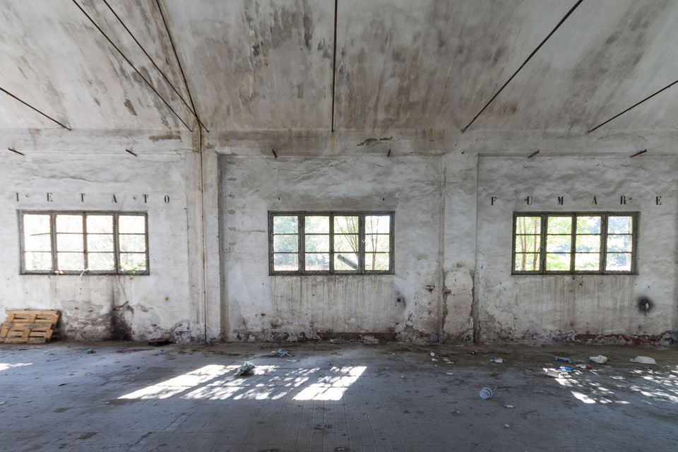 Empty hall with sunlit windows and stencilled lettering on the wall