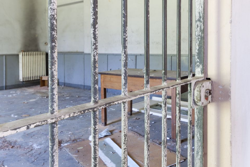 Iron barred gate and a wooden table in a bare room with a radiator