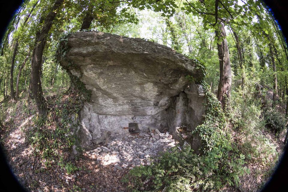 Large rock slab overhanging a rubble-floored recess in the woods