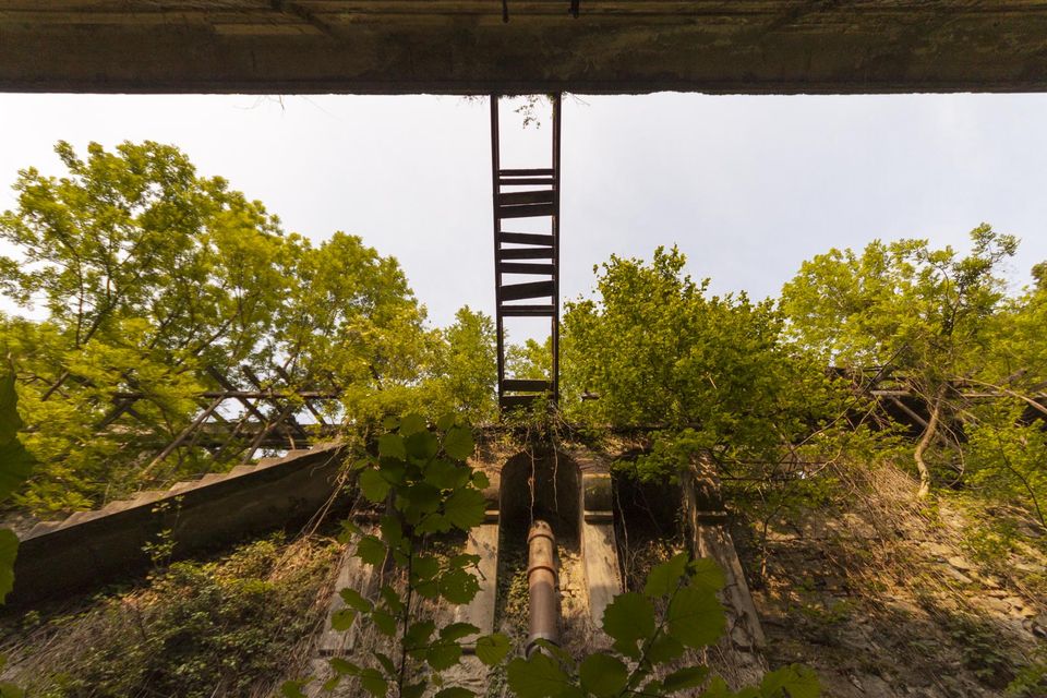 Rusty ladder and pipe seen from below a concrete slab
