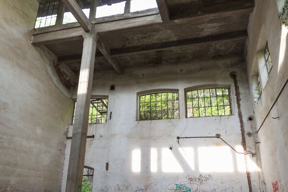 Ruined hall with concrete beams and sunlit windows