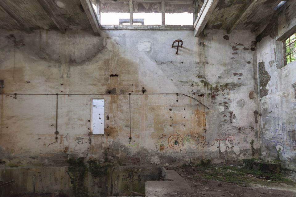 Peeling hall wall with pipework and a small window