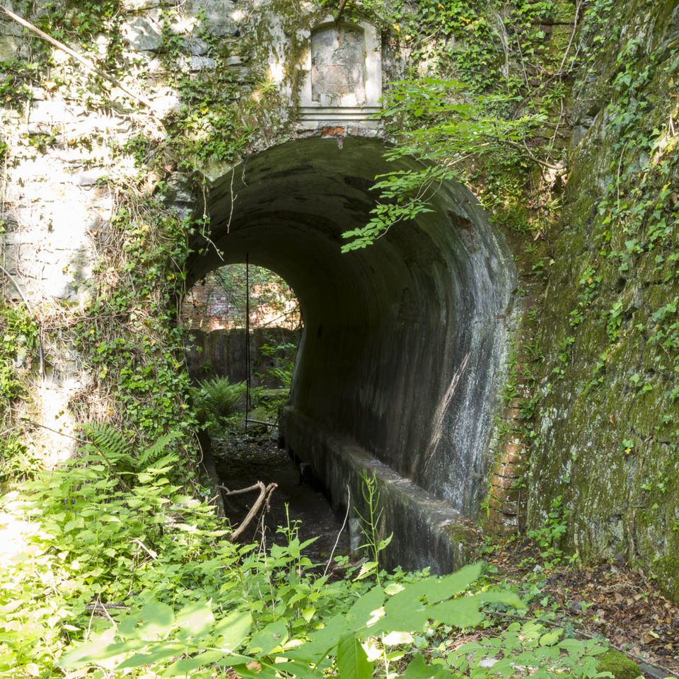 Concrete culvert tunnel under a stone arch with a plaque