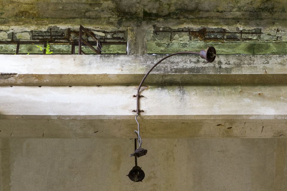 Concrete beam with a rusted lamp bracket and wires