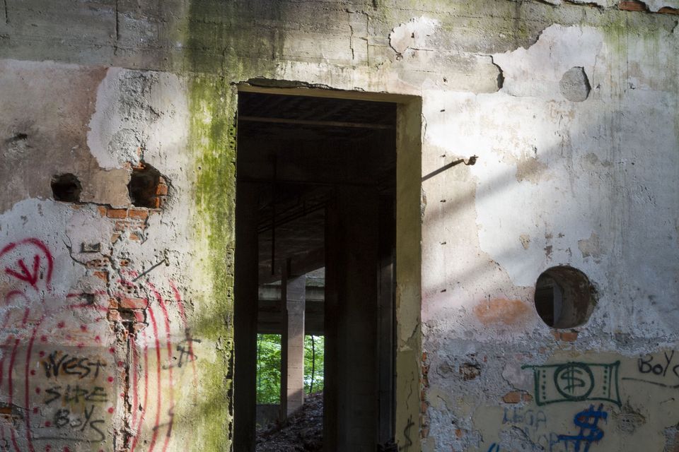 Doorway in a peeling wall with graffiti and round holes