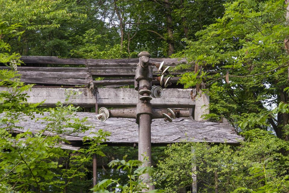 Ceramic insulators on a pole under a rotten wooden roof