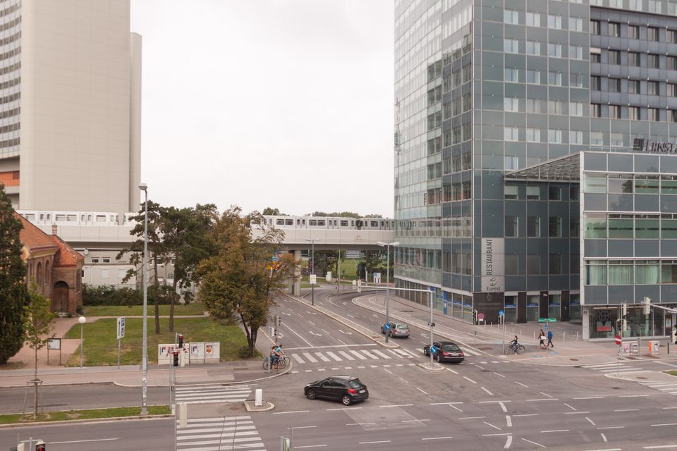 Elevated U-Bahn train crossing a wide junction beside glass office towers