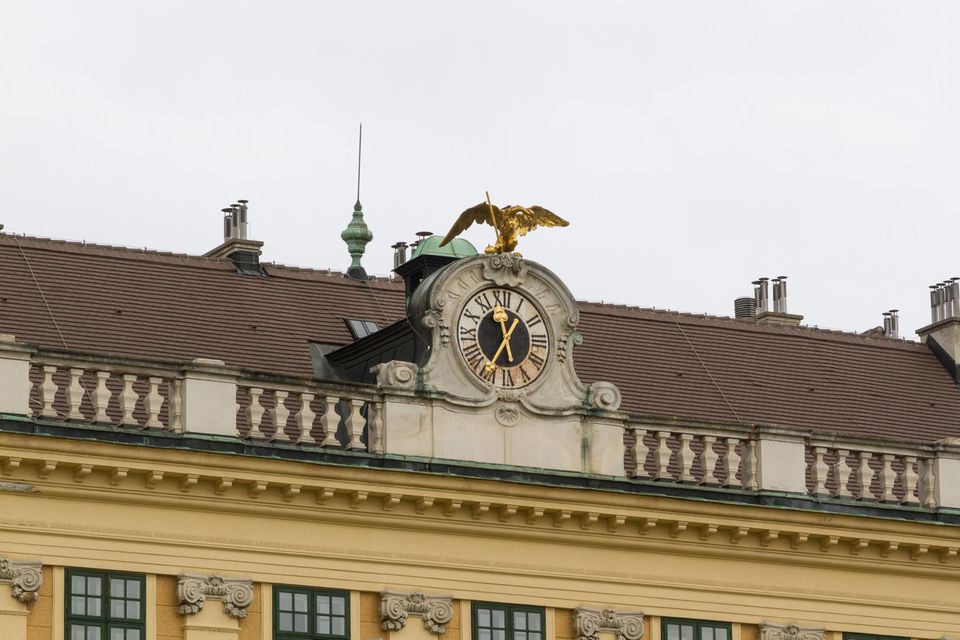 Gilded eagle above a roof clock on a yellow building