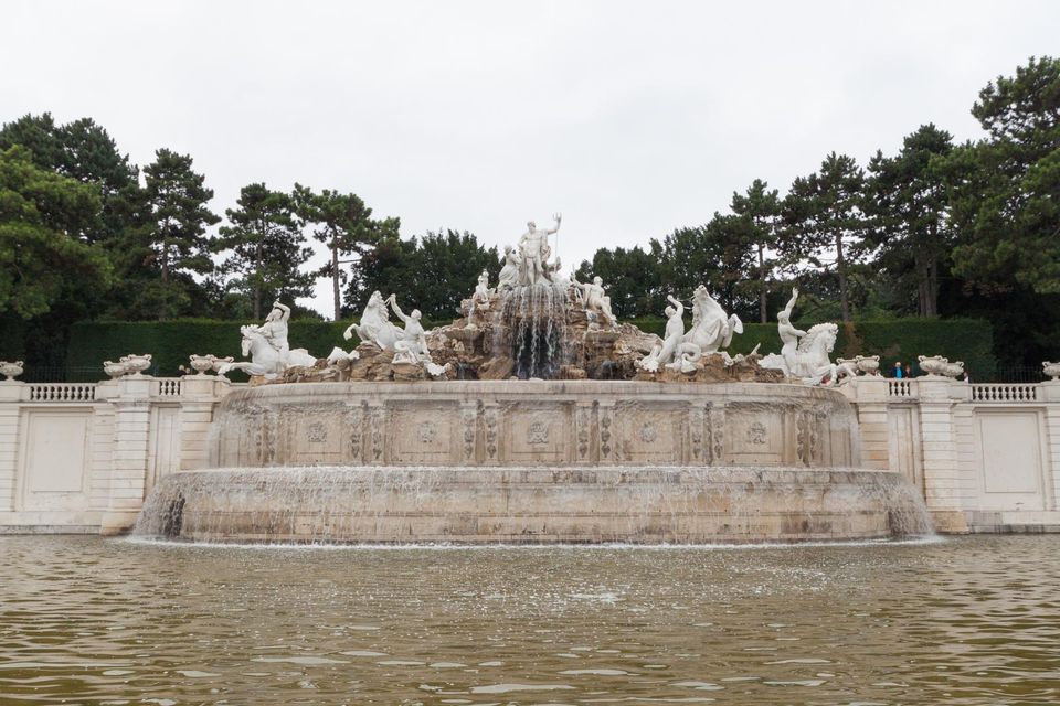 White sculpted fountain with horses and figures in a wide pool
