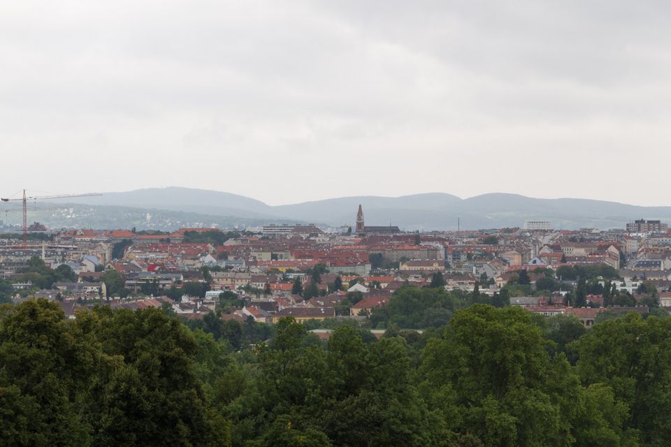 Red rooftops of the city and distant hills beneath a grey sky