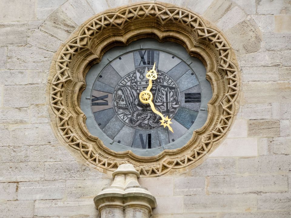 Ornate round clock with golden hands set in carved stone