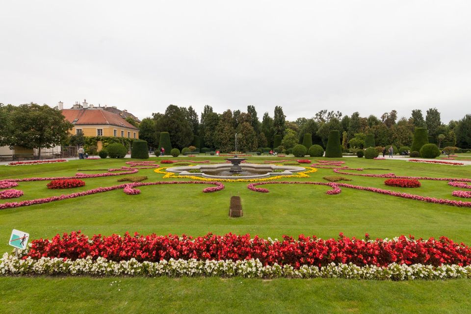 Red and white flower beds around a circular fountain