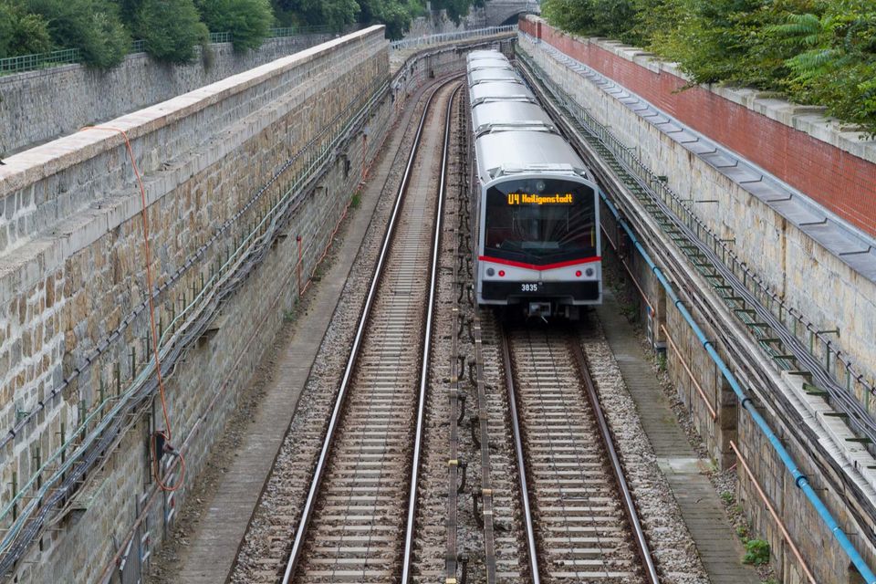 Metro train approaching between tracks in a stone-walled cutting