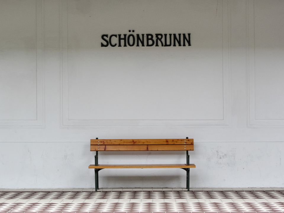 Wooden bench under the Schönbrunn name on a white station wall