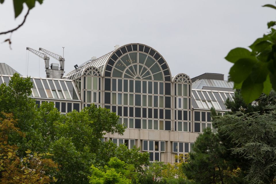 Modern building with an arched glass gable seen through trees