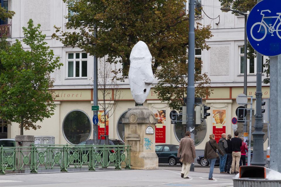 Statue wrapped in white cloth on a stone pedestal at a crossing