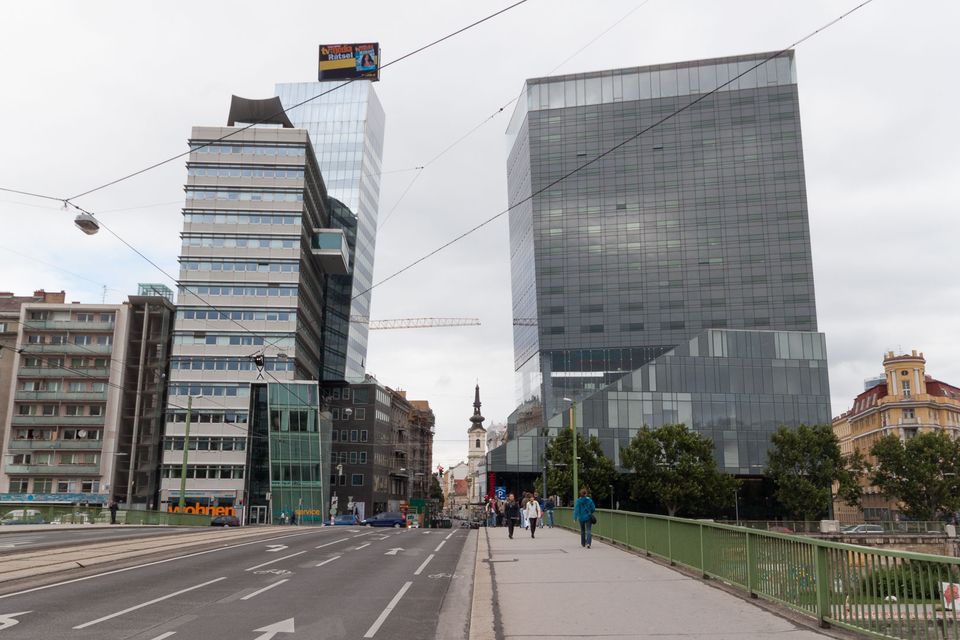 Glass office towers at the end of a bridge with pedestrians