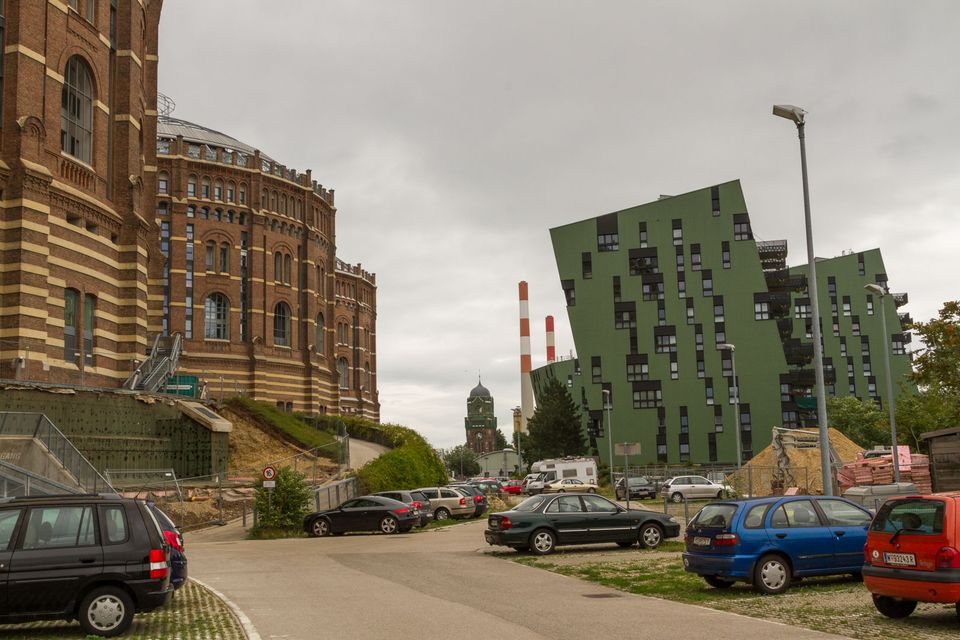 Old brick gasometer beside a tilted green apartment block