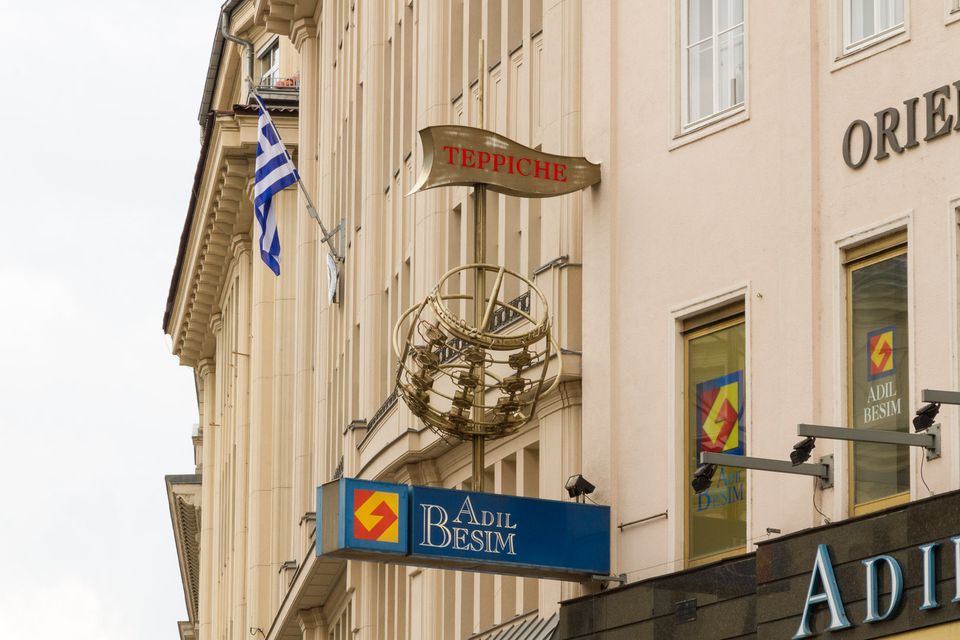 Rug shop sign and Greek flag on a cream building