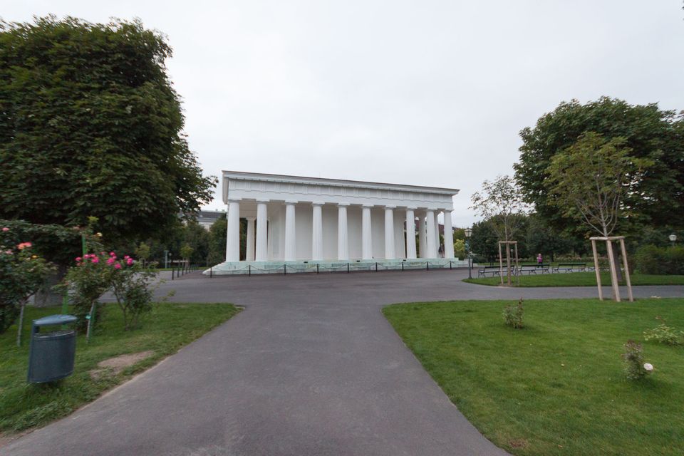 White columned temple beyond a curving path and lawn