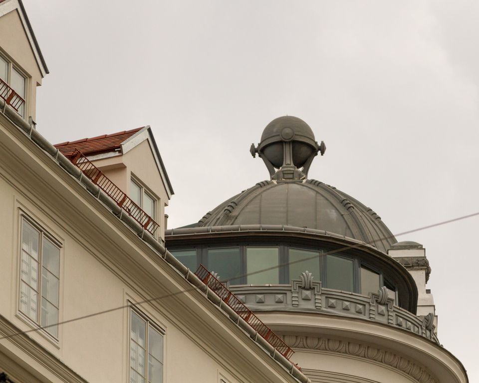 Grey copper dome with a ball finial above cream rooftops