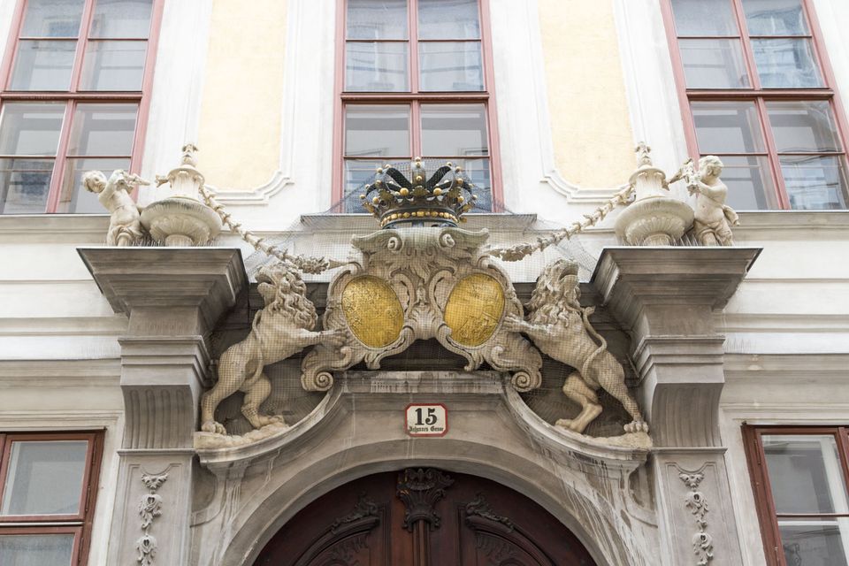 Baroque doorway with stone lions and a crowned golden coat of arms