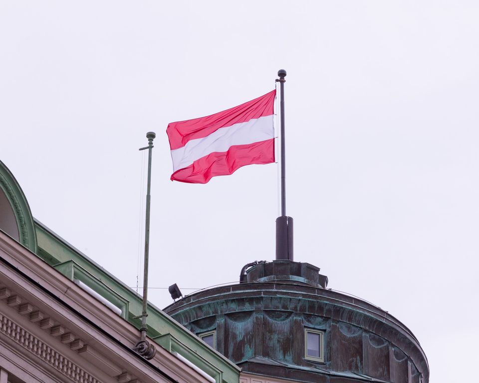 Red-and-white Austrian flag above a verdigris dome