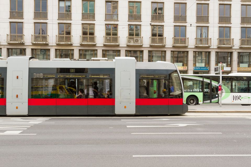 Modern tram passing a pale apartment block