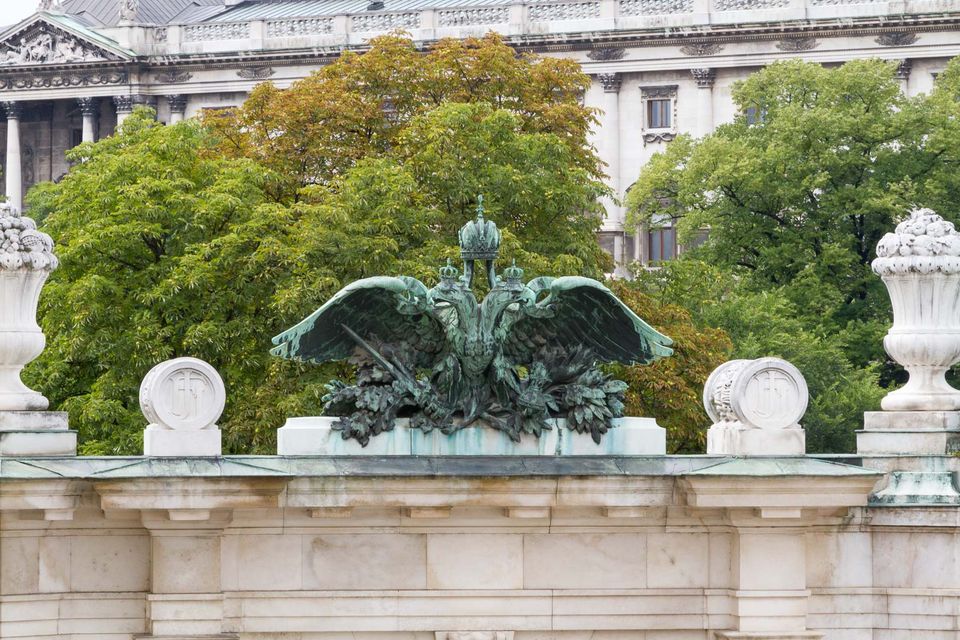 Green bronze eagle on a balustrade in front of trees