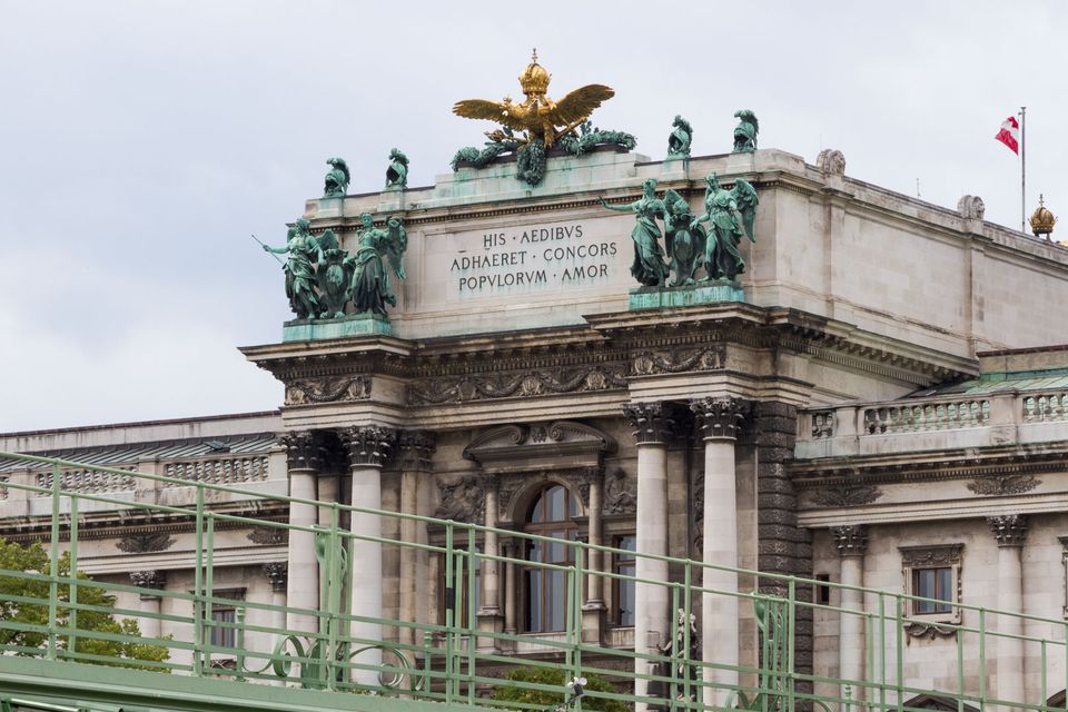 Palace facade with golden eagle and green bronze figures above Latin lettering