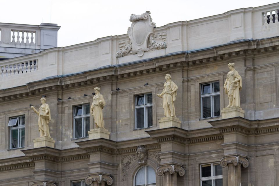 Cream facade with statues on pedestals and a carved cartouche