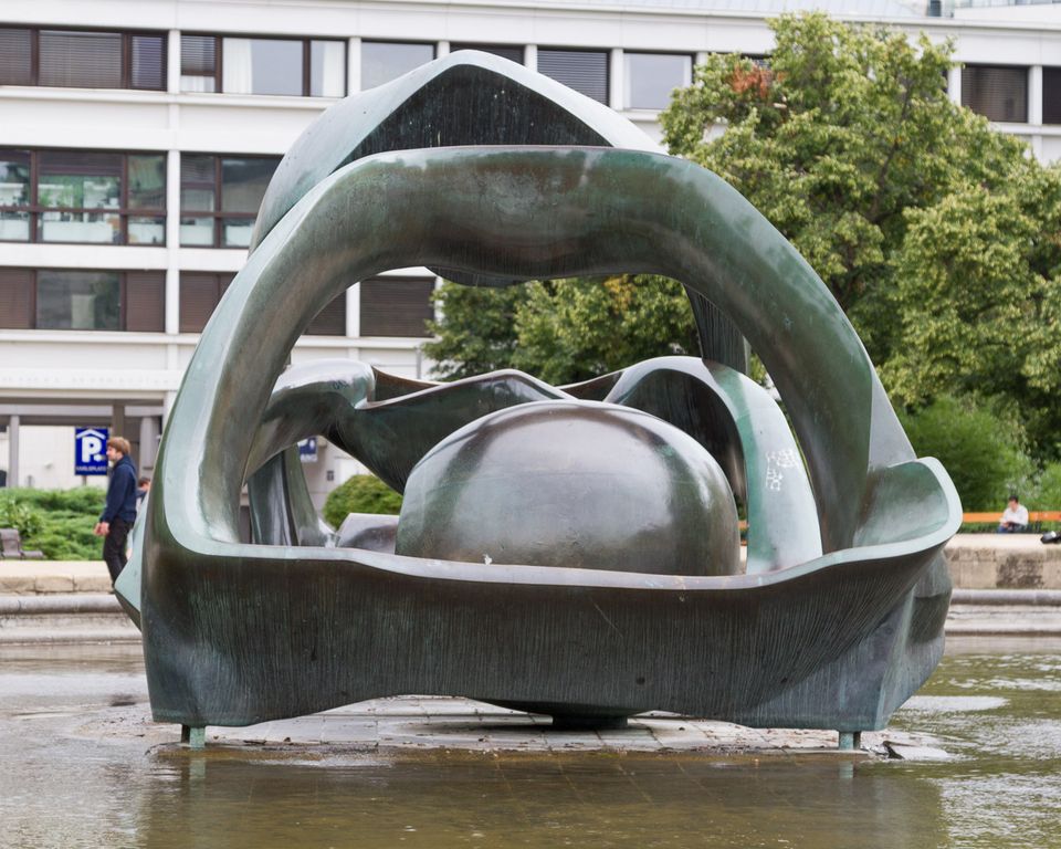 Abstract bronze sculpture in a pond in front of an office block